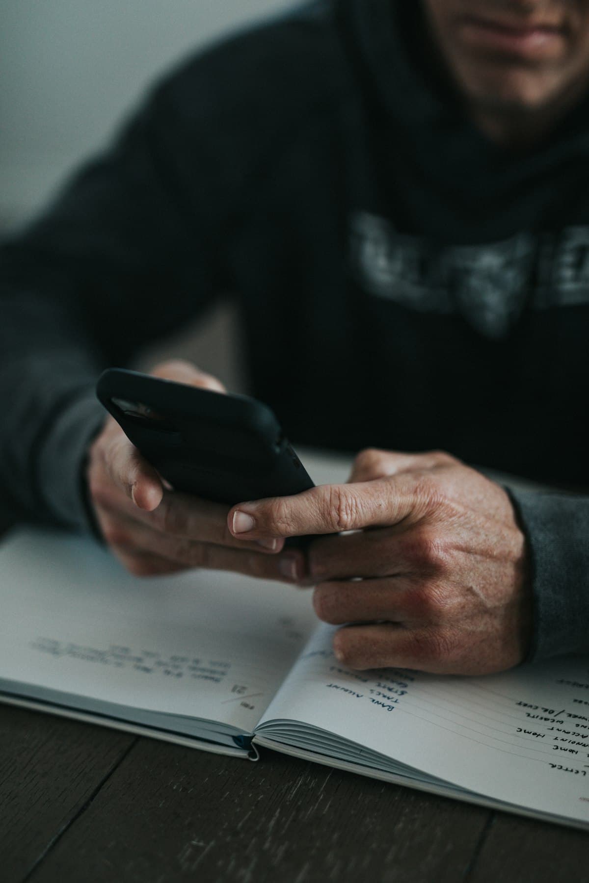 Pessoa organizando as próprias finanças com o celular e anotações